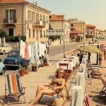 Fotografia d'epoca con turisti e pensioni a gestione familiare lungo la costa di Rimini negli anni del boom economico.