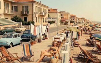 Fotografia d'epoca con turisti e pensioni a gestione familiare lungo la costa di Rimini negli anni del boom economico.