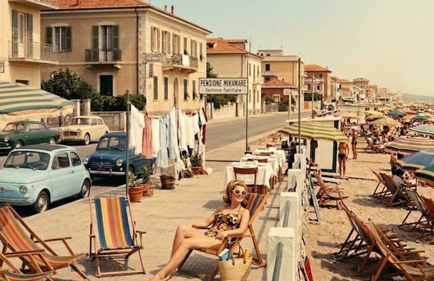 Fotografia d'epoca con turisti e pensioni a gestione familiare lungo la costa di Rimini negli anni del boom economico.